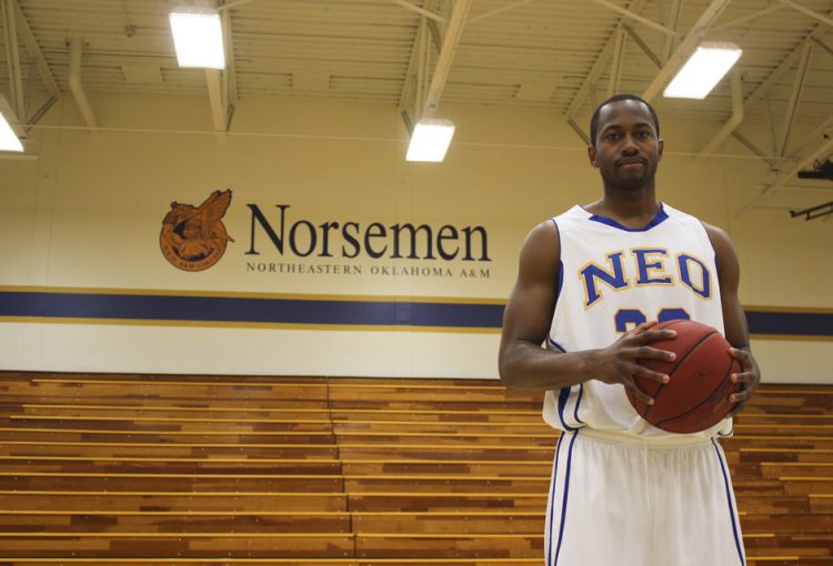 Northeastern Oklahoma A&M Athletics - Posing Next to Logo